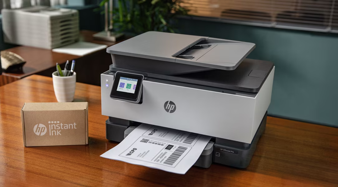 HP business printer and Instant Ink box on a desk. Stock photography for illustrative context, not a catalogue or official brand photograph.